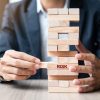Businessman hand placing or pulling wooden block on the tower. Business planning, Risk Management, Solution and strategy Concepts